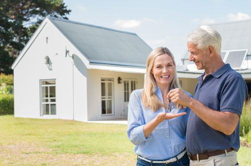 Ein lächelndes Paar steht mit einem Schlüsselbund in der Hand vor einem Haus