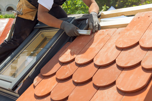 Ein Handwerker repariert ein Dach an einem Dachfenster